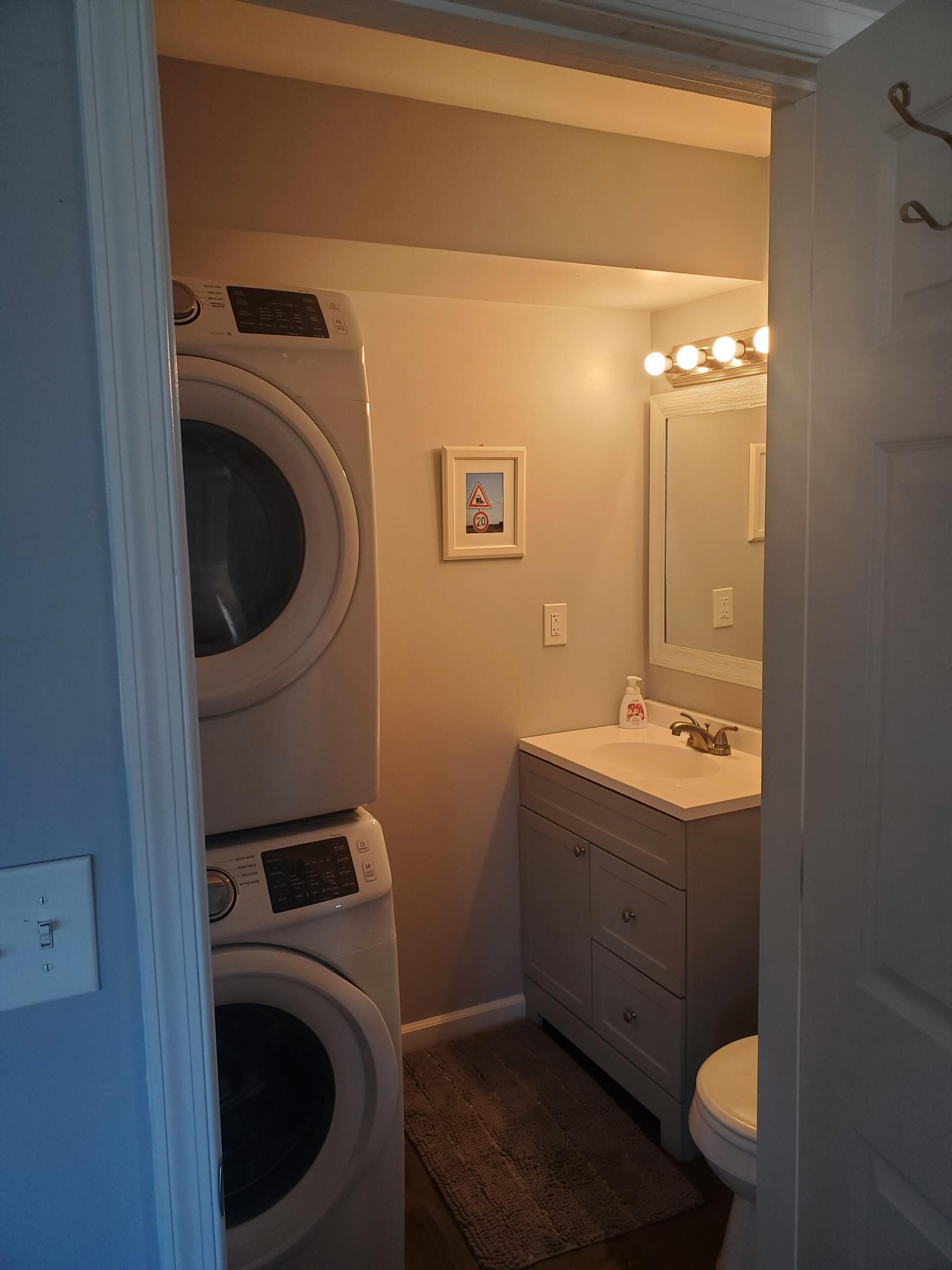 A compact bathroom with a washing machine, a sink, and a toilet.
