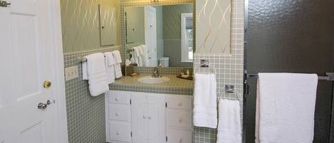 A bathroom with a white door, a sink with a mirror above it, and a towel rack with multiple towels.