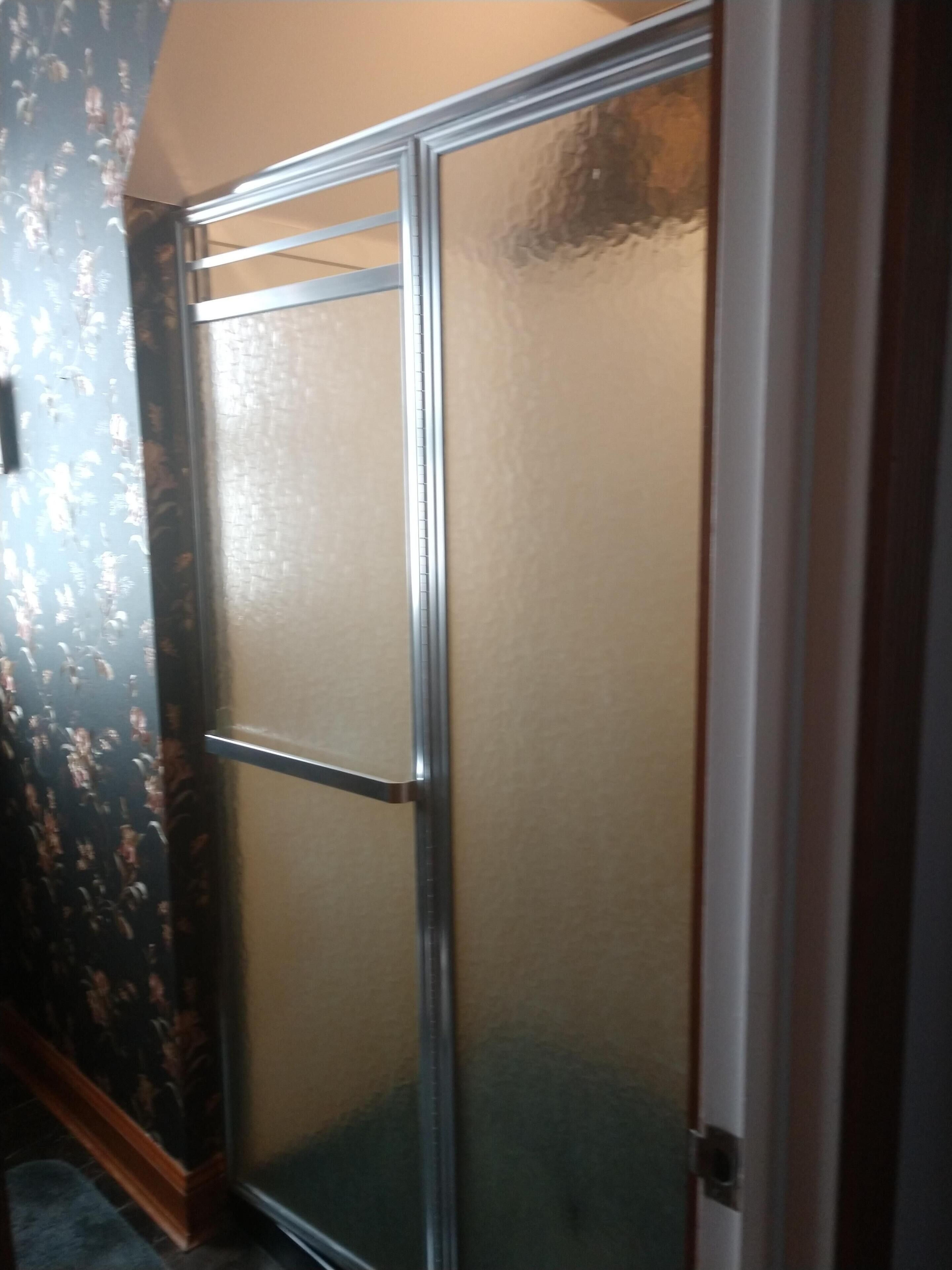 Una habitación con puerta corrediza de vidrio, papel tapiz estampado y piso de madera.
