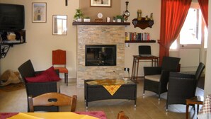 A living room with a stone fireplace, wicker furniture, a television, and bookshelves.