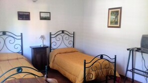 Una habitación con dos camas, un escritorio pequeño y un televisor.