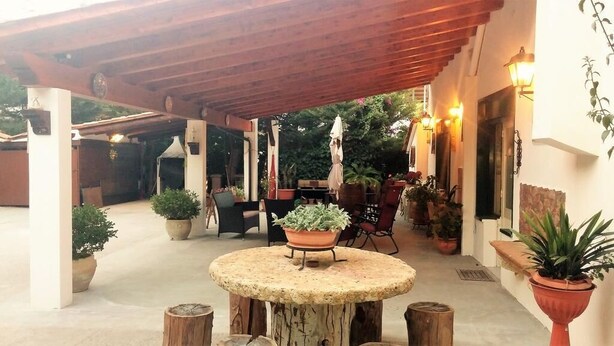 An outdoor patio area with a round table, potted plants, and a covered seating area.