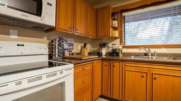Una cucina con mobili in legno, un forno a microonde, un fornello e una finestra con persiane.