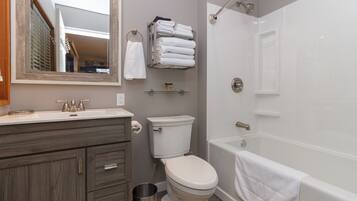 Een badkamer met toilet, wastafel, badkamermeubel en bad.