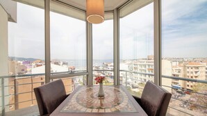A balcony with a table, chairs, and a hanging light fixture. - Çanak Hotel (Çanakkale)