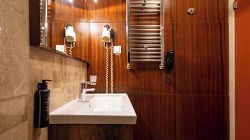 A modern bathroom with a wooden vanity, a large mirror, and a towel rack.