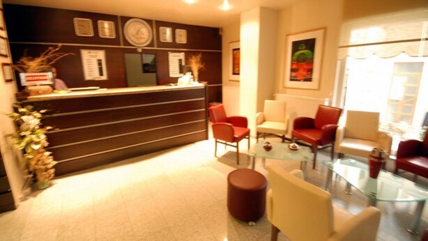 A reception area with a counter, red and white chairs, and a glass coffee table. - Çanak Hotel (Çanakkale)