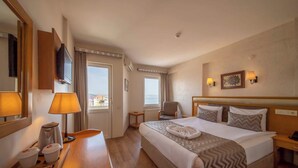 A hotel room with a bed, bedside table, lamp, TV, and a view of the sea. - Çanak Hotel (Çanakkale)