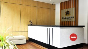 A reception desk with a sign for LAA ADAMS and a logo for OYO. - Laa Adams (Hatton)