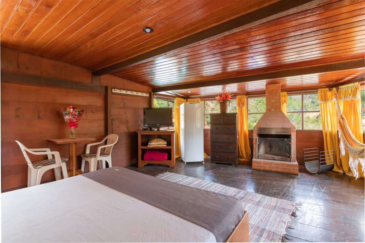 Une chambre dans un chalet en bois, comprenant un lit, une télévision, une cheminée et un coin repas.