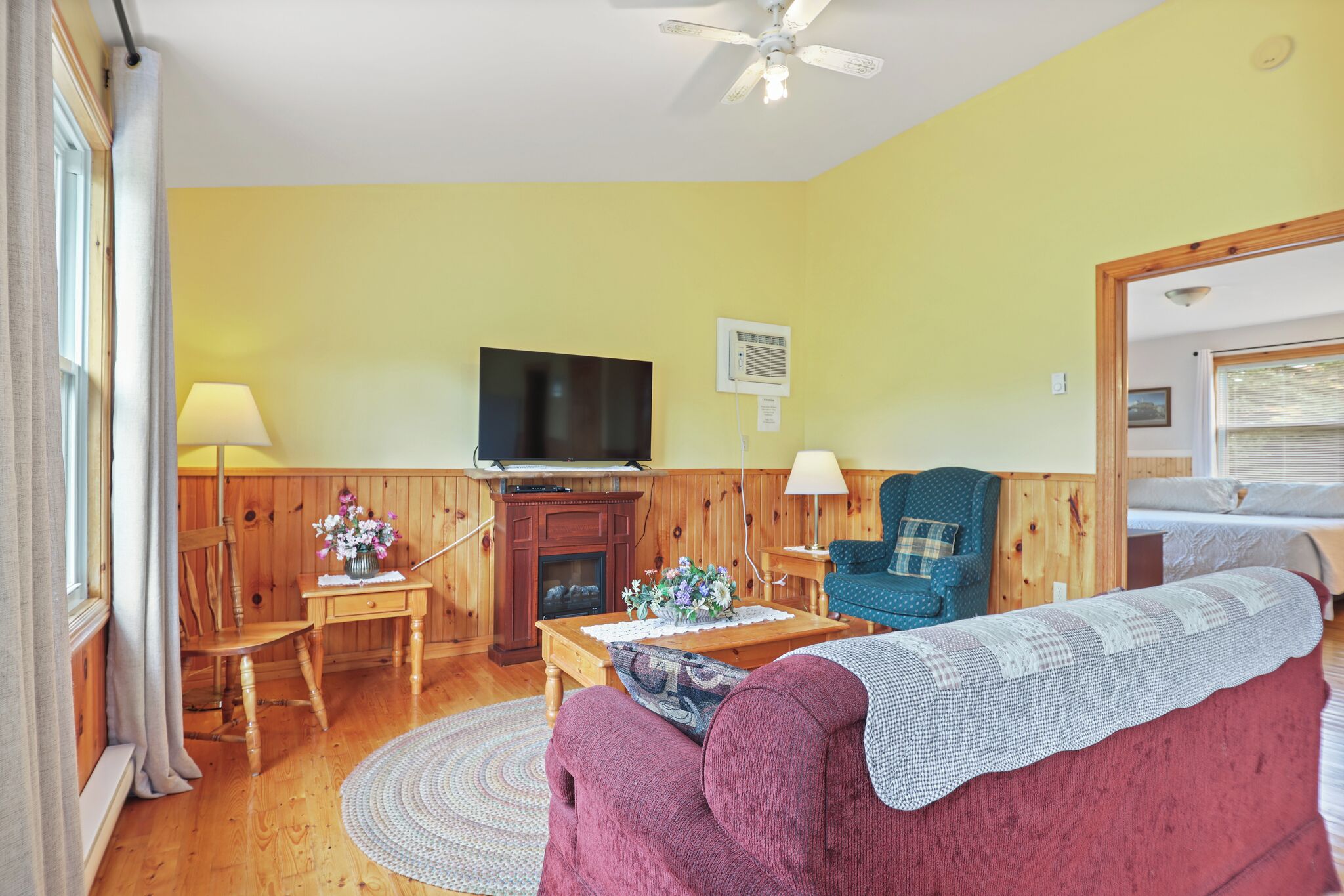 A cozy living room with a wooden floor, a television, a fireplace, a sofa, and a chair.