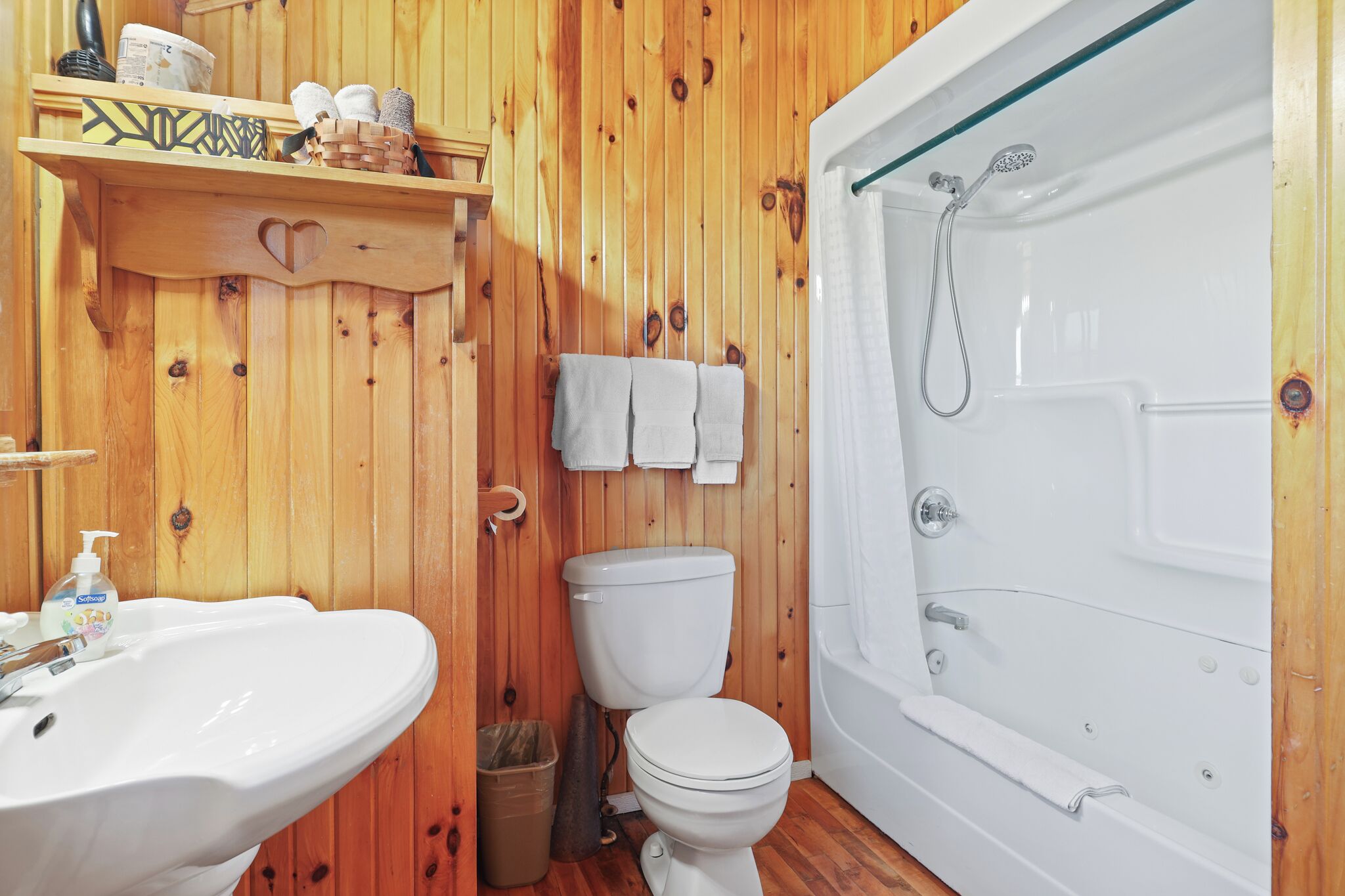 Un baño con pared de madera, lavamanos, inodoro y bañera.
