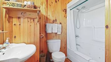 Un baño con pared de madera, lavamanos, inodoro y bañera.