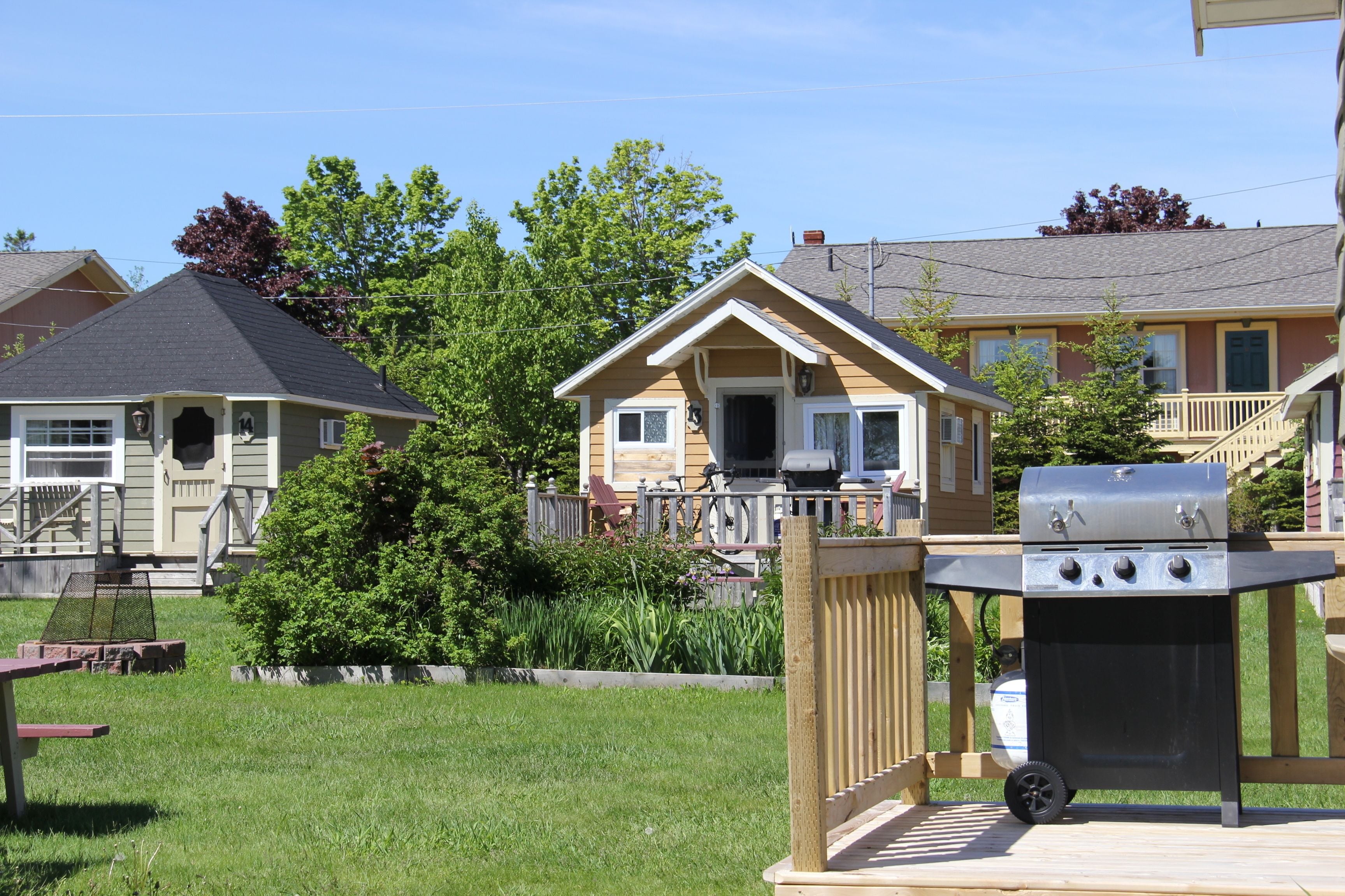 Un quartier résidentiel doté d’une terrasse en bois, d’un barbecue et d’une maison avec un porche.