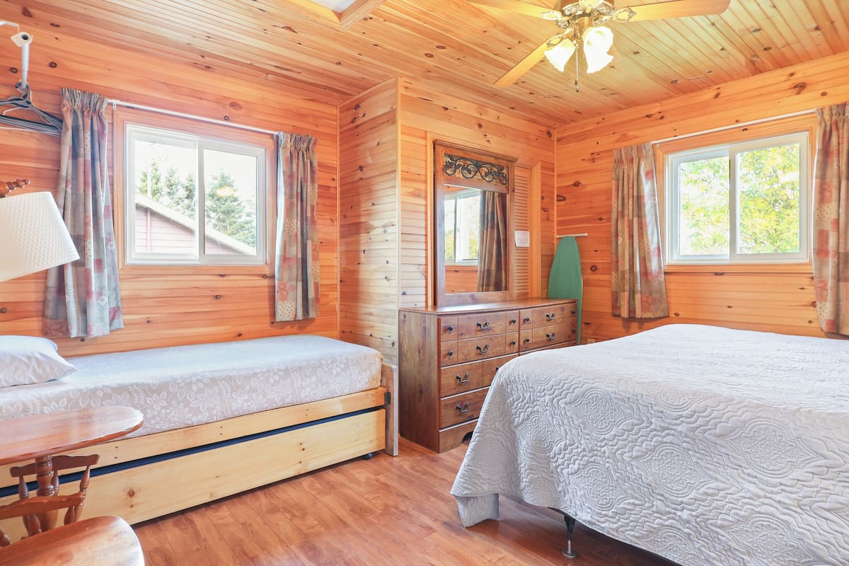 Ein Schlafzimmer einer Holzhütte mit zwei Betten, einem Schminktisch und einem Tisch.