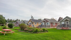 Un hilera de casas de un piso con porches, una mesa de picnic y un césped bien cuidado.