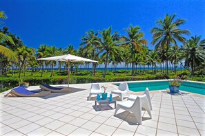 A poolside area with white lounge chairs, a white umbrella, and a potted plant. - Villa Talanquera (Samaná)