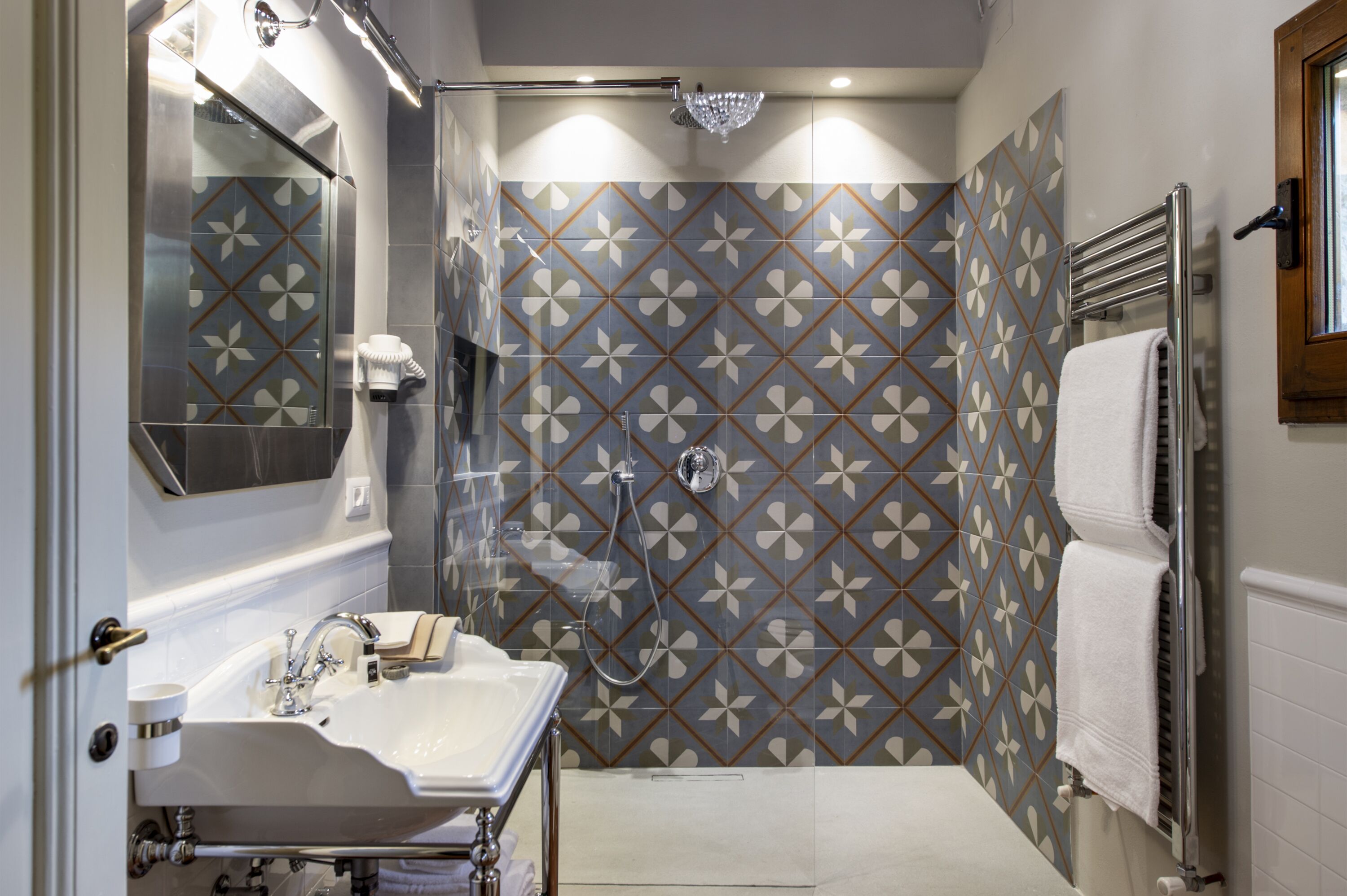A bathroom with a shower, a sink, and a towel rack.