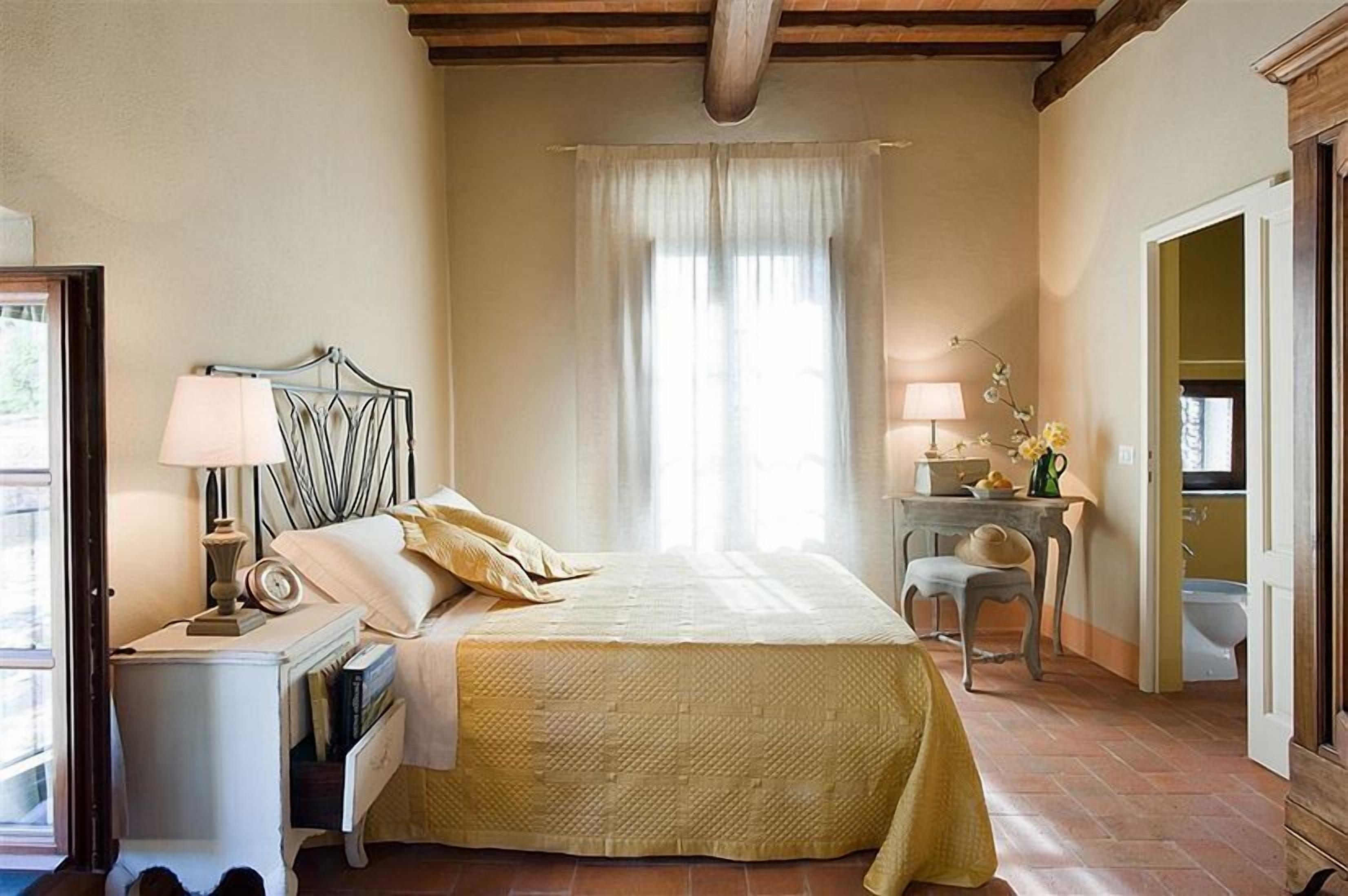A bedroom with a bed, bedside table, lamp, and a window with curtains.