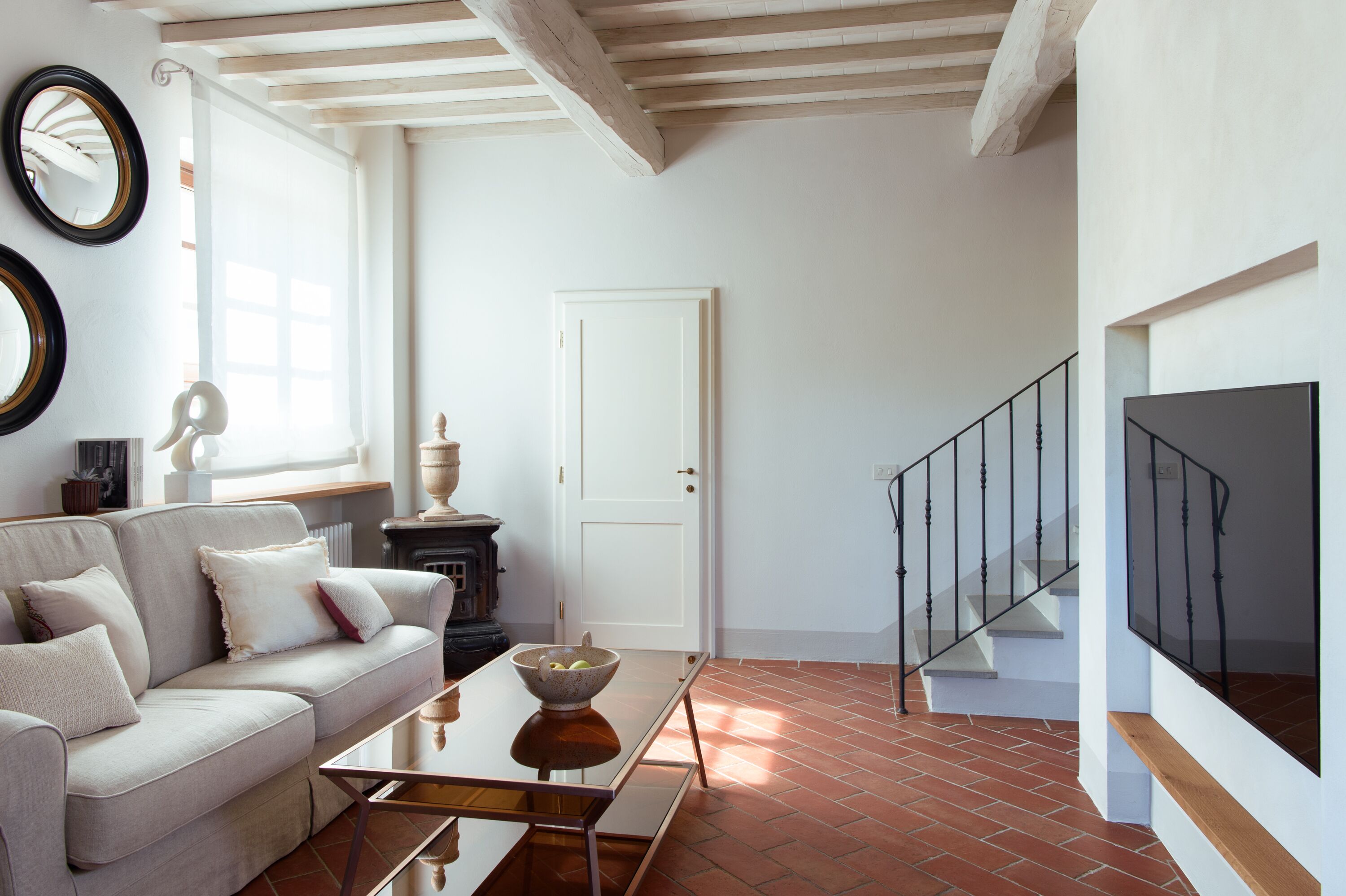 Ein Wohnzimmer mit einer Couch, einem Couchtisch und einem Kamin. Eine Treppe mit Geländer führt zu einer weiteren Ebene.