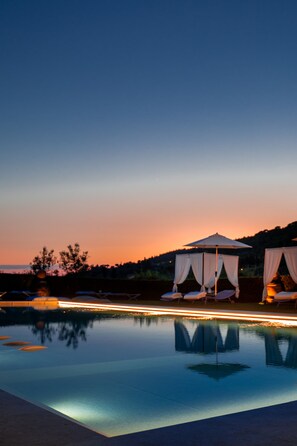 A serene pool area at dusk with two canopied lounge chairs and a clear reflection on the water. - Borgo I Vicelli Adults Only Relais (Bagno a Ripoli)