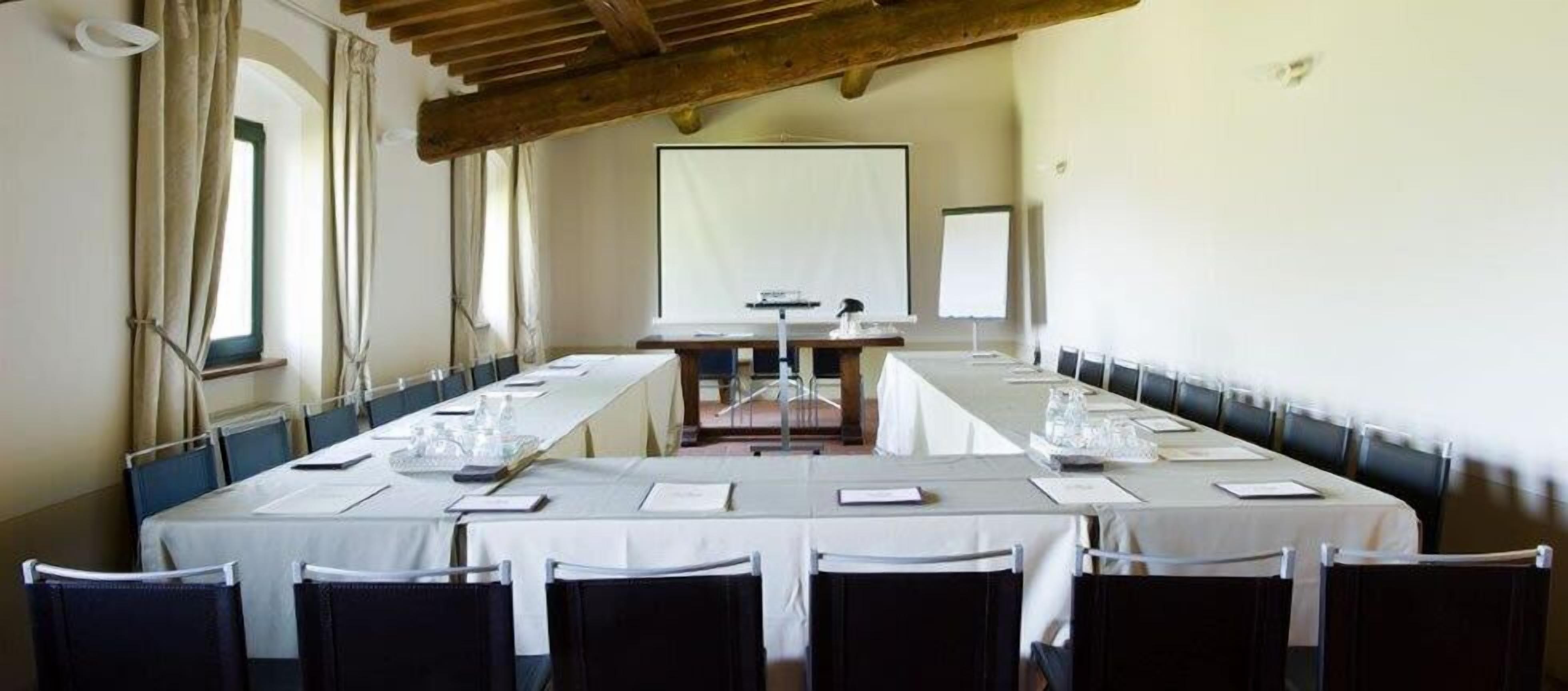 A conference room with a long table, chairs, a projector, and a screen.