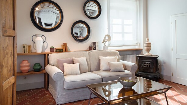 A cozy living room with a sofa, a glass coffee table, and a vintage stove. - Borgo I Vicelli Adults Only Relais (Bagno a Ripoli)