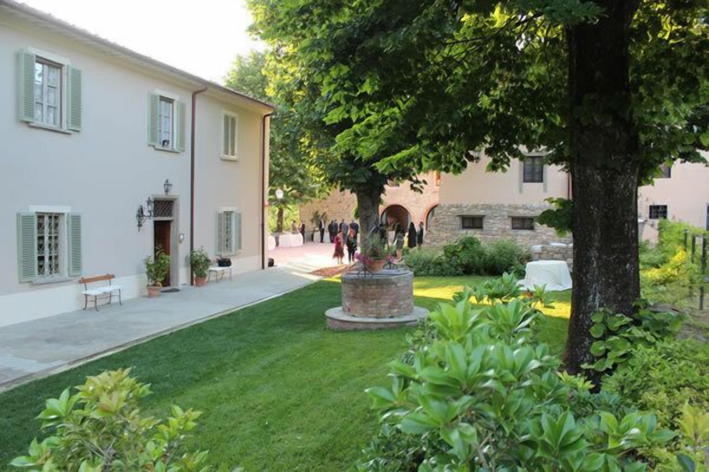 Un patio con un edificio, una estatua y un árbol.