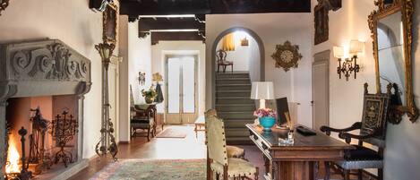 Un interior tradicional con chimenea, muebles ornamentados y una escalera que lleva a otra habitación.