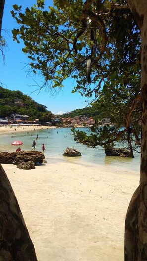 Ein Strand mit klarem Wasser, Felsen und einigen Personen.