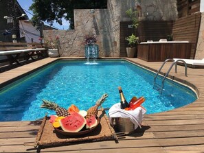 Ein Poolbereich mit Holzterrasse, Steinmauer und Whirlpool.