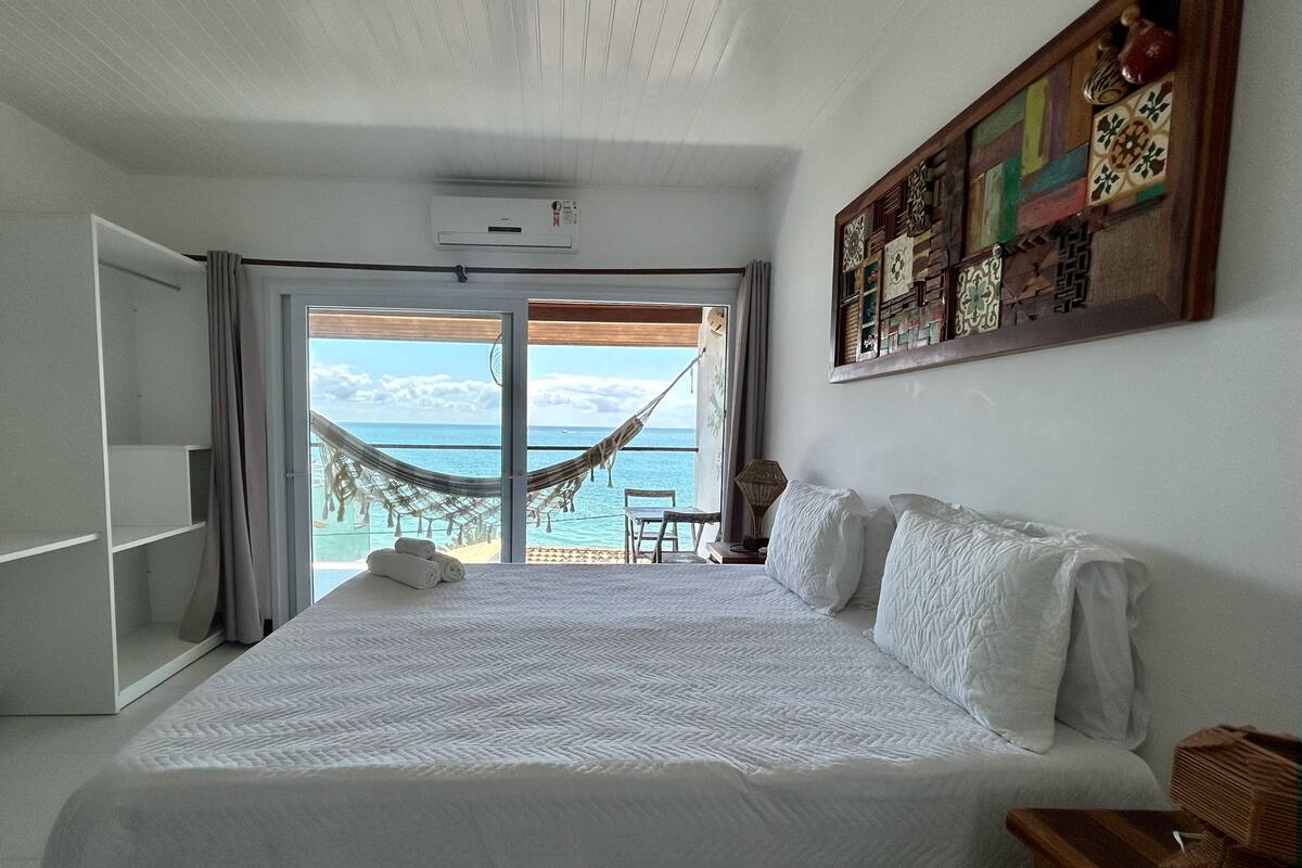Un dormitorio con una cama grande, una hamaca y vistas al océano.