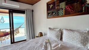 Habitación de hotel con una cama grande, techo de madera, vista a la playa y un panel decorativo en la pared.