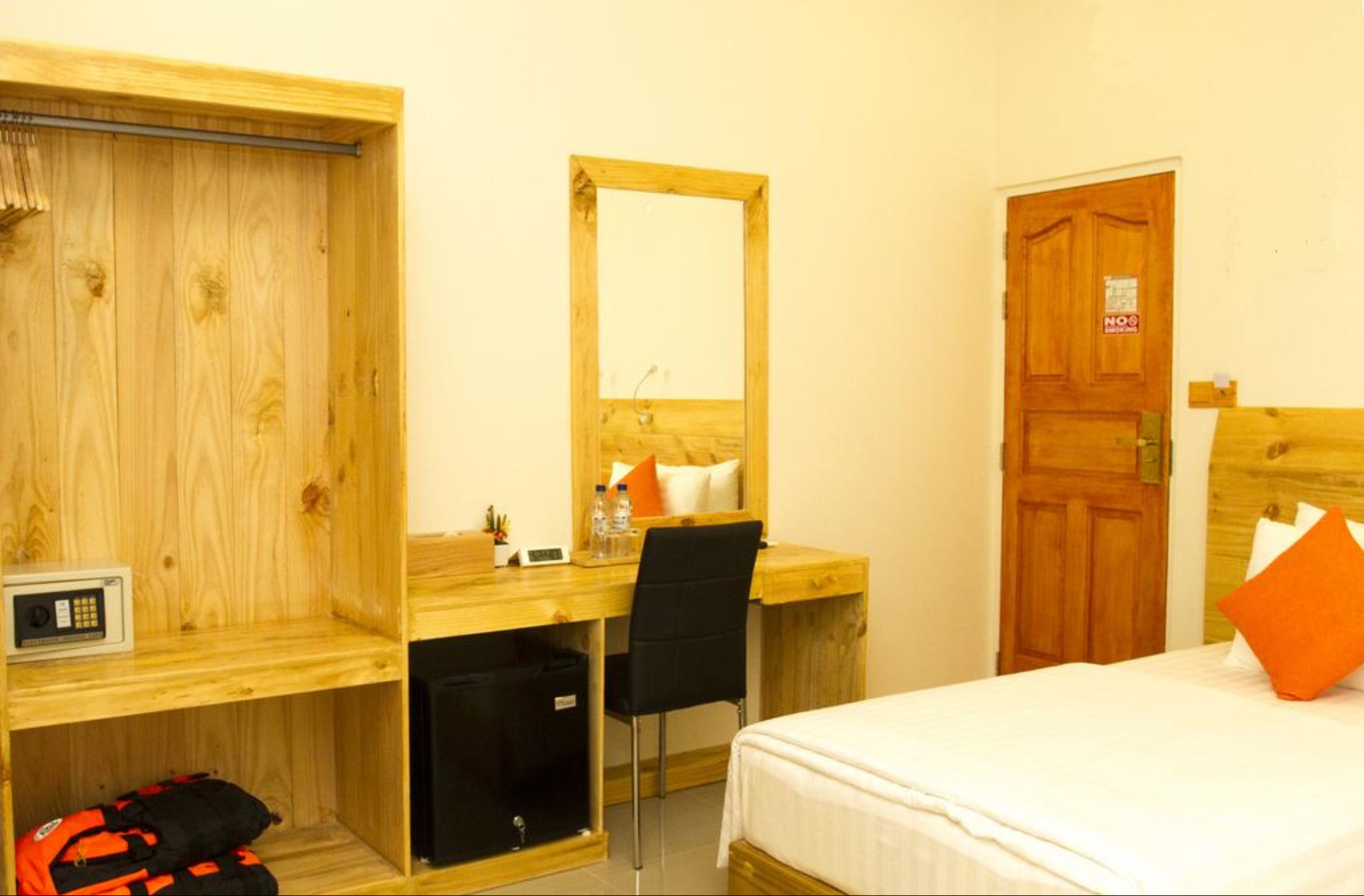 Habitación de hotel con escritorio de madera, una silla, una cama, un armario y una puerta.
