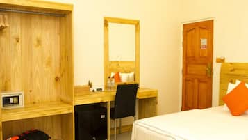 Habitación de hotel con escritorio de madera, una silla, una cama, un armario y una puerta.