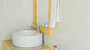 A bathroom with a white sink, a wooden vanity, a mirror, and a towel rack with folded towels.