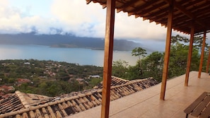 A wooden pergola overlooking a coastal town with a view of the sea and mountains.