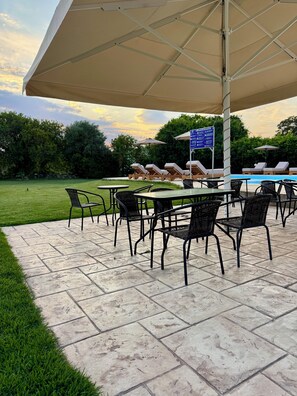 Une terrasse extérieure avec des chaises longues, une piscine et un espace salon abrité.