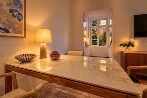 Une pièce bien éclairée, avec une table en marbre, une lampe, des objets décoratifs et une vue par la fenêtre.
