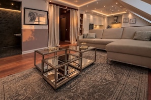 Un salon moderne avec une table basse en verre, un canapé beige et un tapis à motifs.