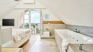 A modern bedroom with a large bed, a built-in TV, and a balcony with a view. - Boutique Suites and Residences Heidelberg – Alte Zigarrenmanufaktur (Heidelberg)