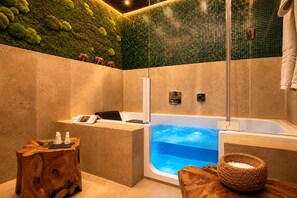 Ein modernes Badezimmer mit einer großen Badewanne, einem hölzernen Hocker und einem kleinen Tisch mit einem Buch und Flaschen.