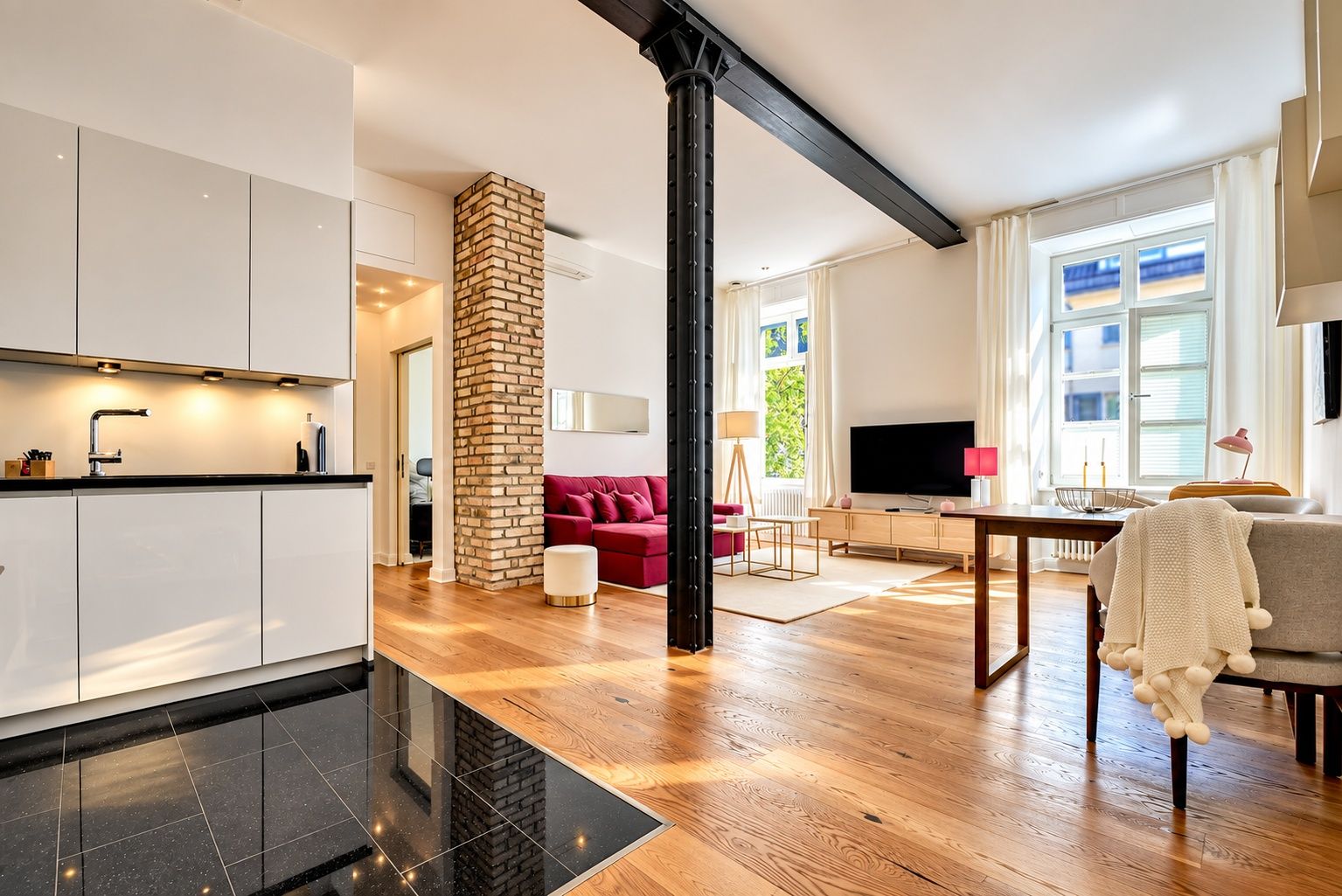 A modern living space with a kitchen, a red sofa, a TV, and a dining area.