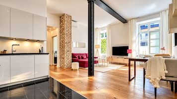 A modern living space with a kitchen, a red sofa, a TV, and a dining area.