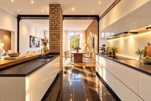 Une cuisine moderne avec un îlot central, un coin repas avec des chaises et un mur d’accent en briques.
