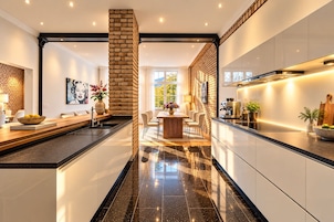 Een moderne keuken met een centraal eiland, een eethoek met stoelen en een accentmuur van baksteen.