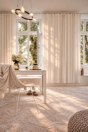 A room with a white chair, a table with a vase of flowers, and a coffee pot. - Boutique Suites and Residences Heidelberg – Alte Zigarrenmanufaktur (Heidelberg)