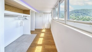 A modern hallway with a wooden floor, a built-in drying rack, and large windows offering a view of a forested hillside. - Boutique Suites and Residences Heidelberg – Alte Zigarrenmanufaktur (Heidelberg)