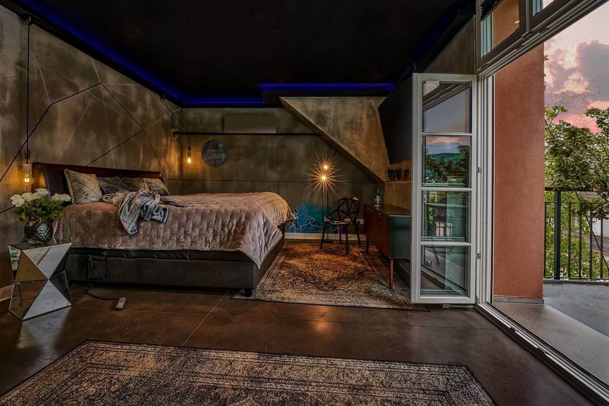 Ein modernes Schlafzimmer mit einem großen Bett, einem Schreibtisch und Blick ins Freie.