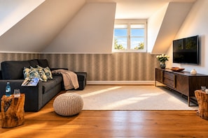 Ein modernes Wohnzimmer mit einer Couch, einem Hocker und einer Unterhaltungsanlage.